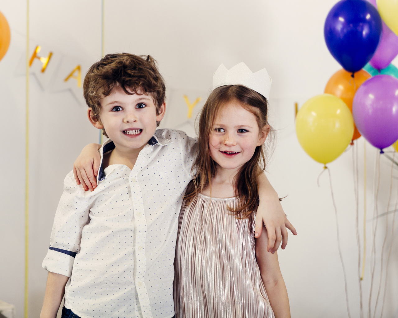 Маленькие мальчик и девочка на празднике с воздушными шарами