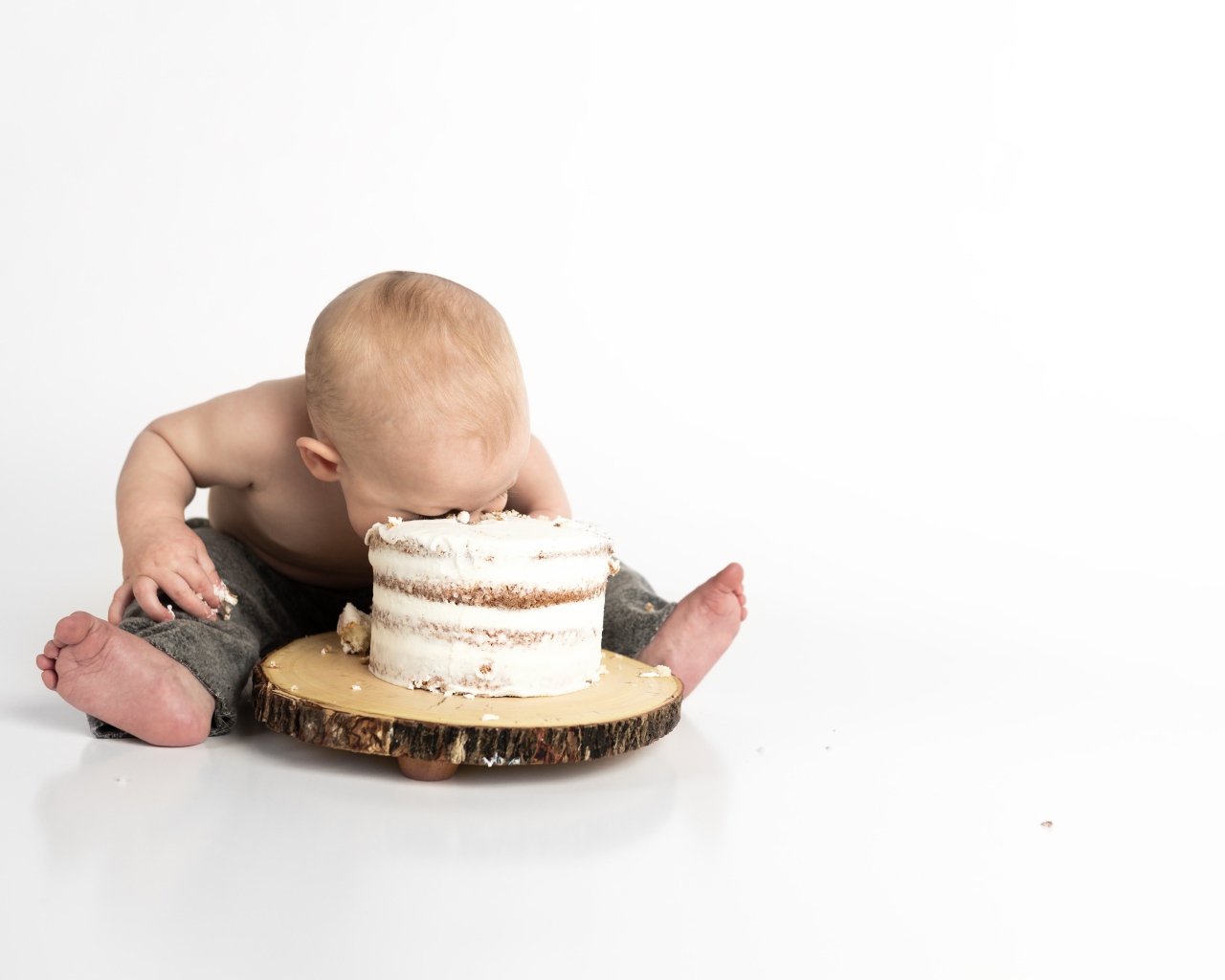 Маленький мальчик ест торт на белом фоне