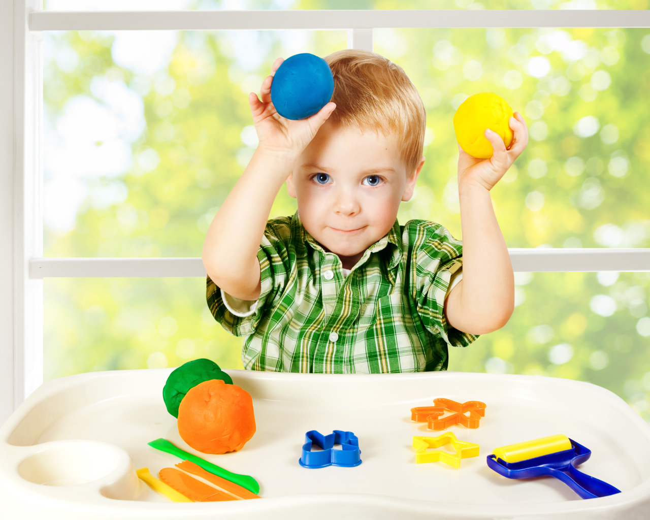 Маленький мальчик играет с игрушками у окна
