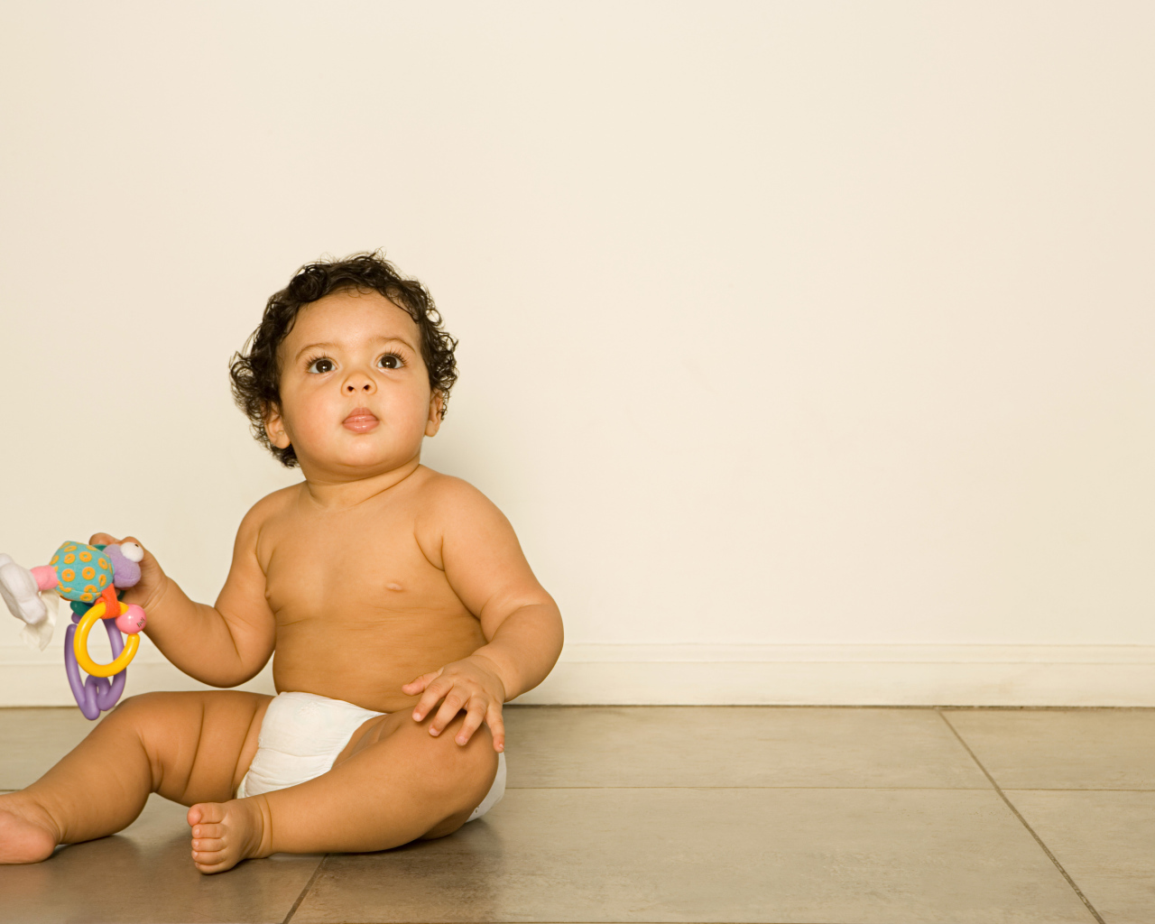 Маленький мальчик сидит на полу с игрушкой