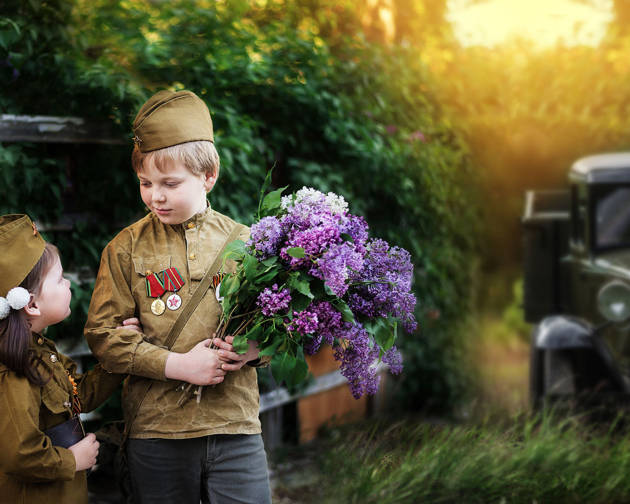 Маленький мальчик с девочкой в военной форме с букетом сирени на 9 мая 