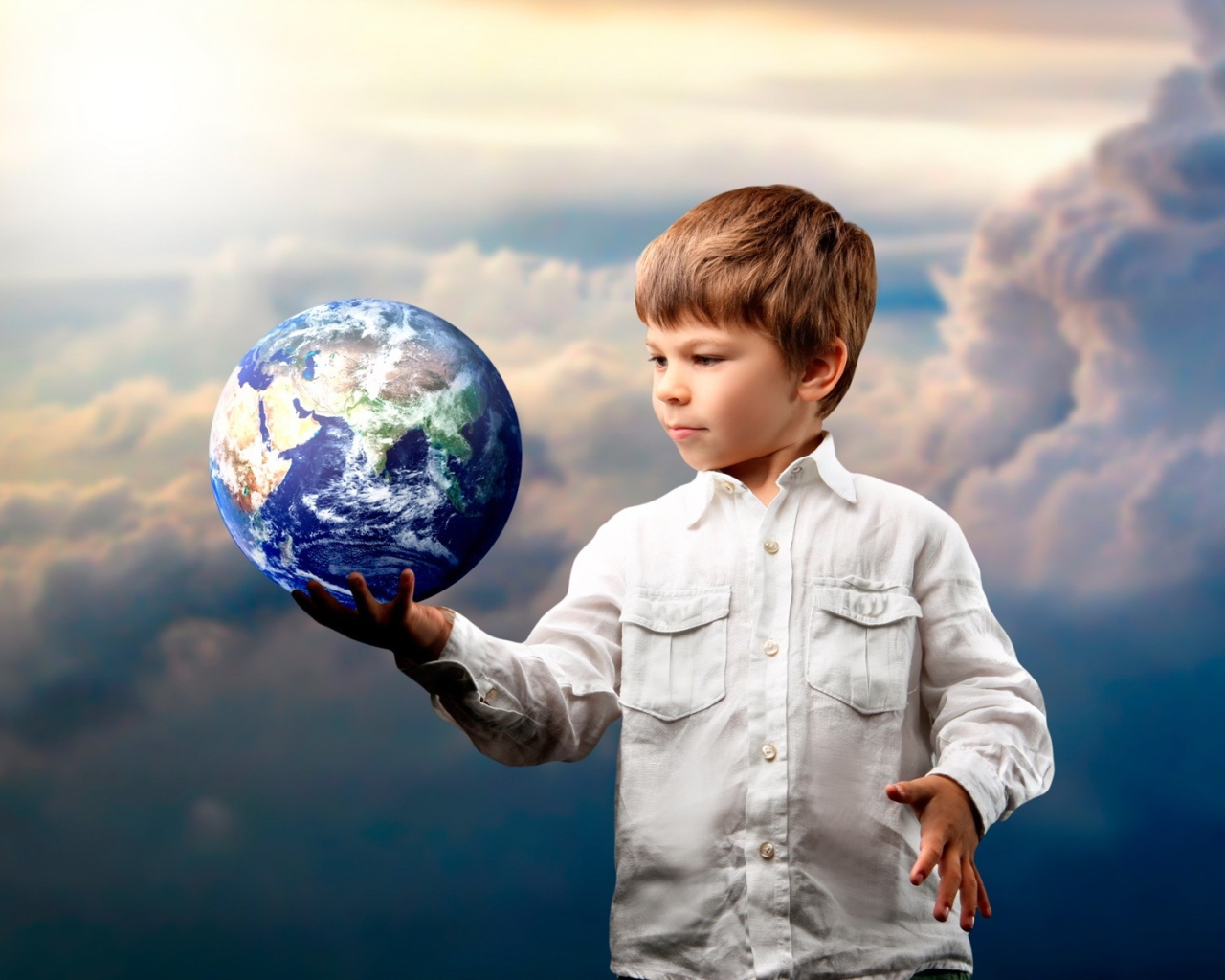 Маленький мальчик с планетой земля в руке