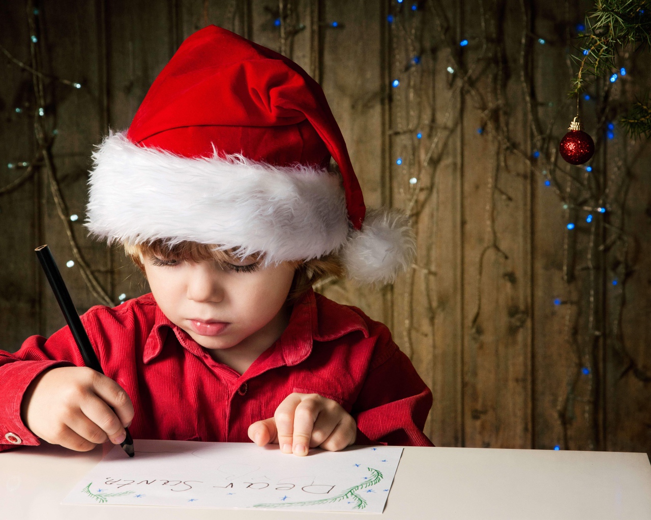 Маленький мальчик пишет письмо Деду Морозу 