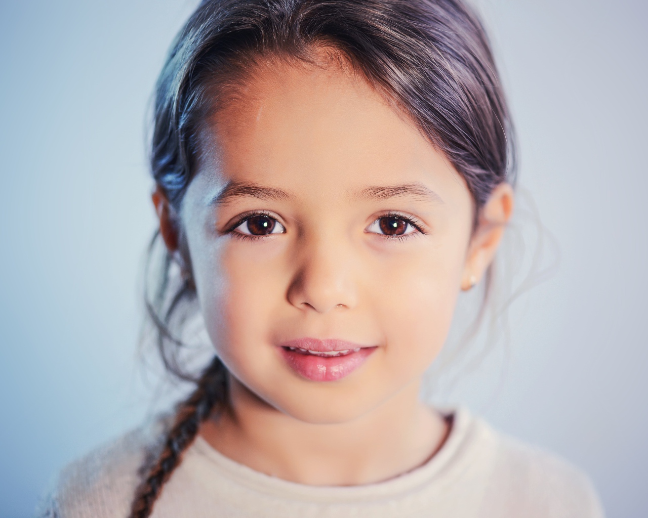 Маленькая кареглазая девочка на сером фоне