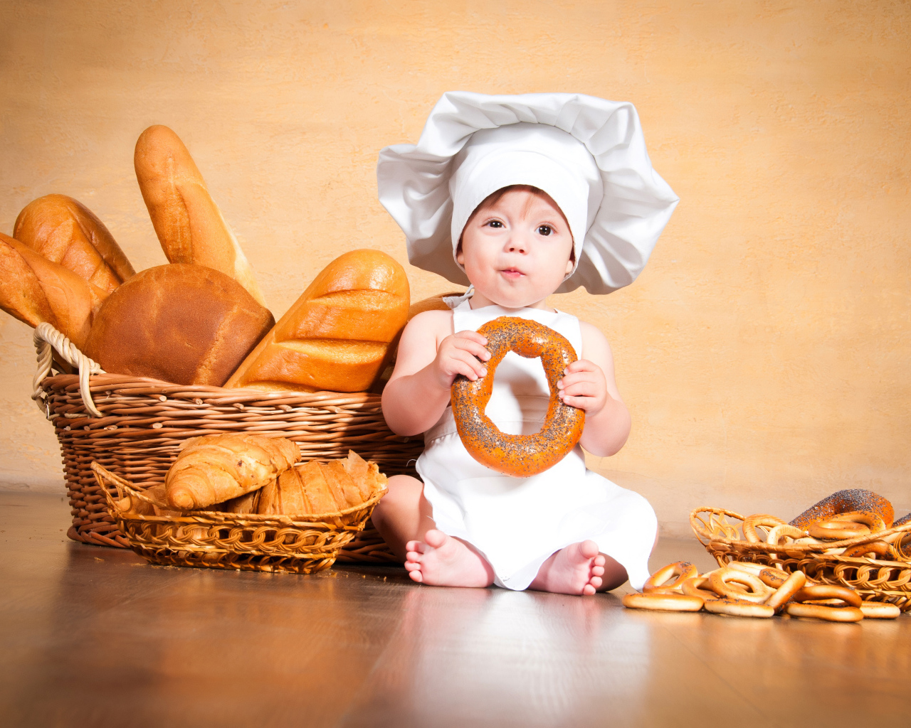 Маленький поваренок на столе со свежей выпечкой