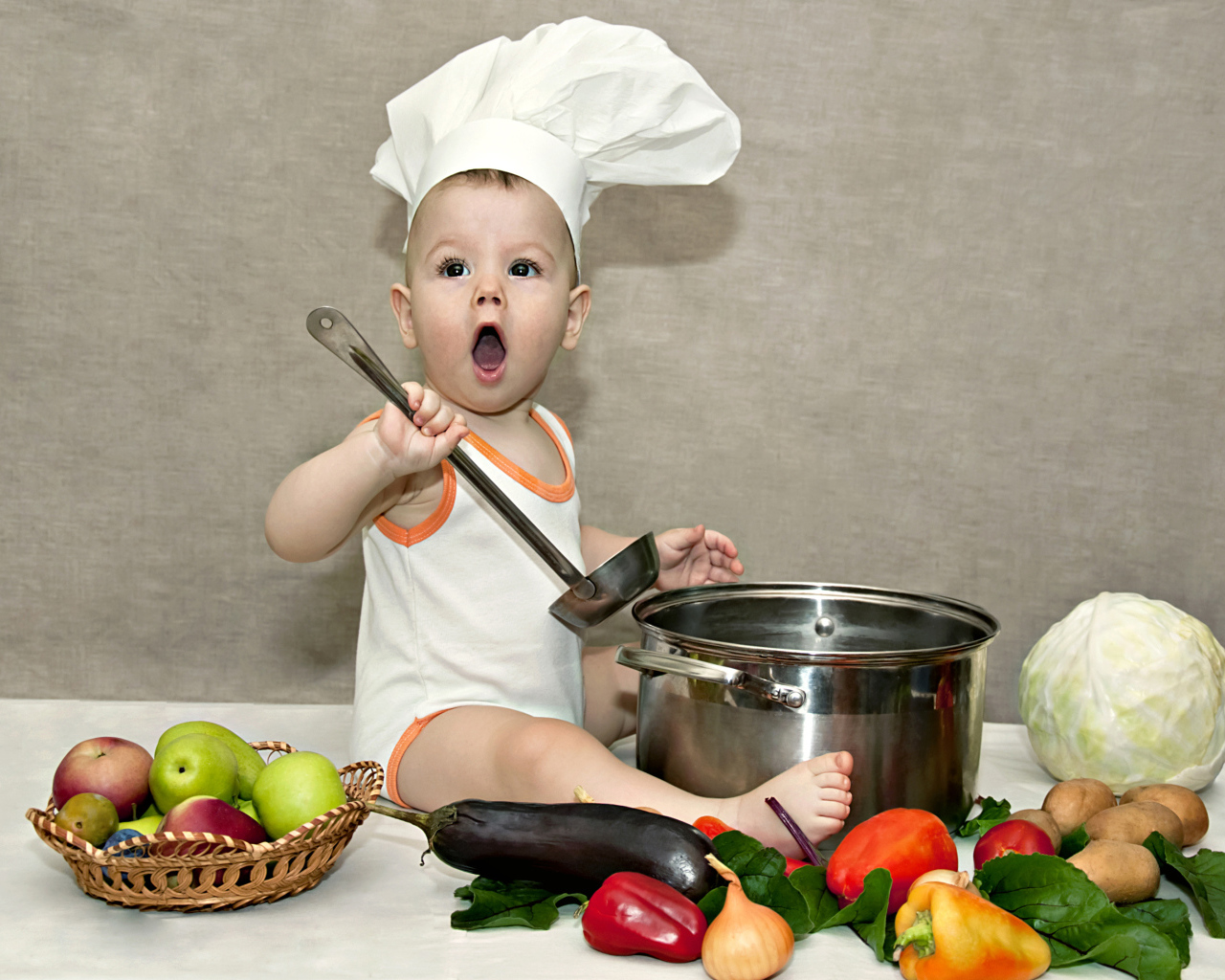 Маленький поваренок с кастрюлей на столе с овощами