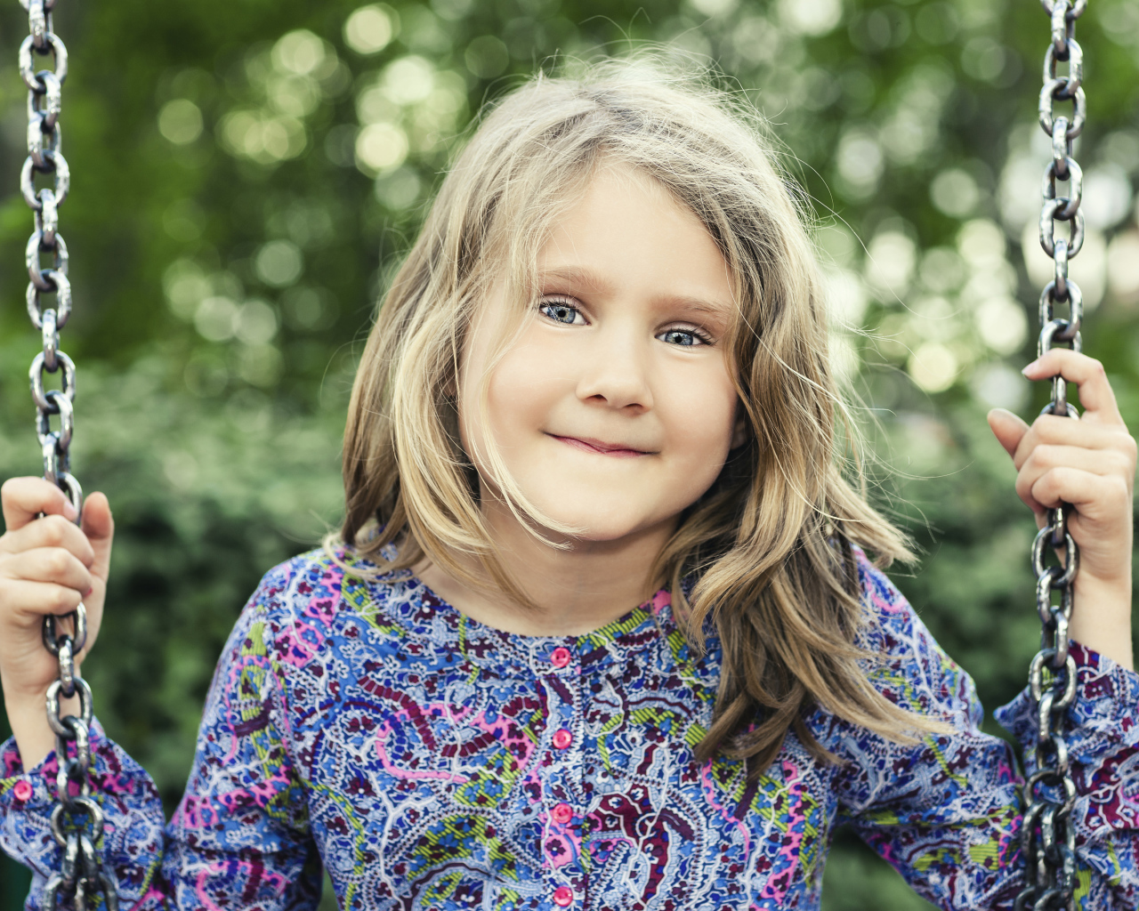 Маленькая милая голубоглазая девочка на качели