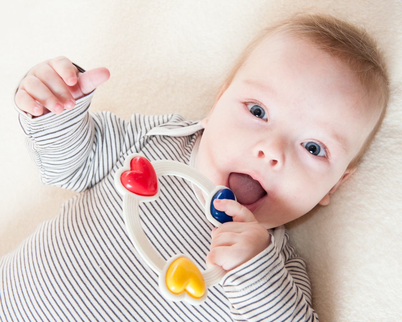 Маленький забавный голубоглазый ребенок с погремушкой