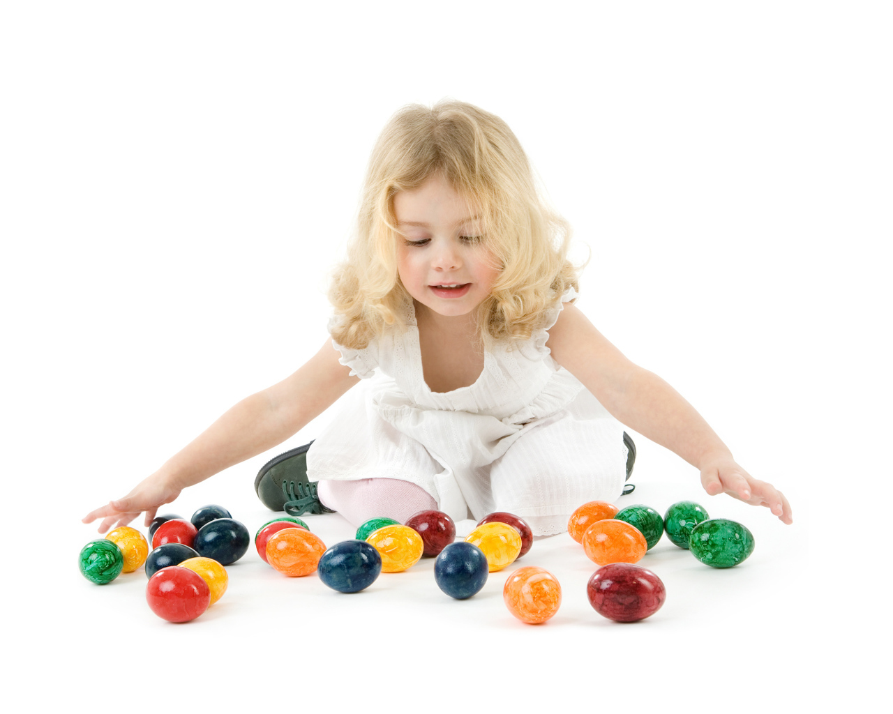 Маленькая девочка блондинка с крашеными яйцами на белом фоне