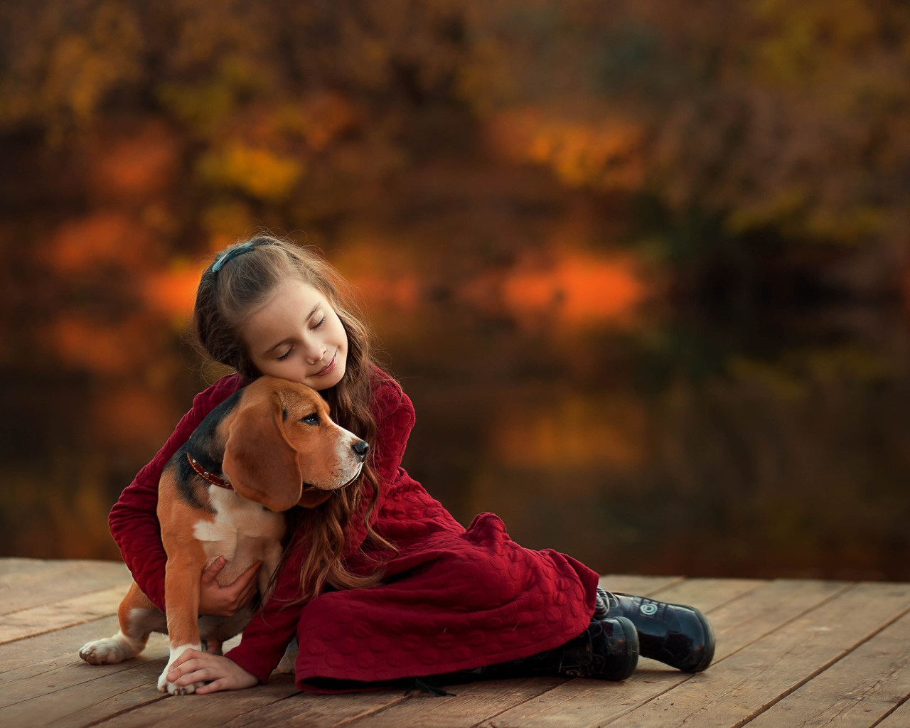 Маленькая девочка обнимает собаку породы бигль на мосту