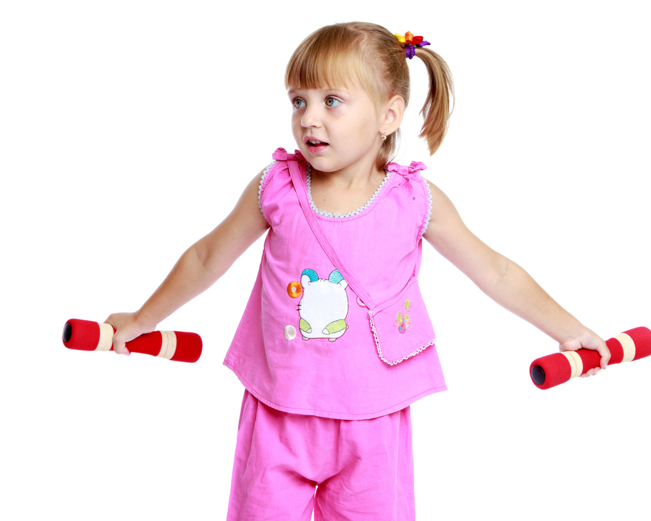 Маленькая девочка в розовом костюме с гантелями в руках на белом фоне
