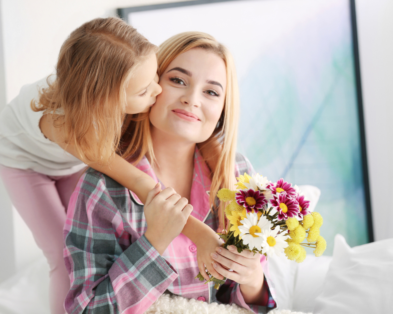 Маленькая девочка целует маму с букетом