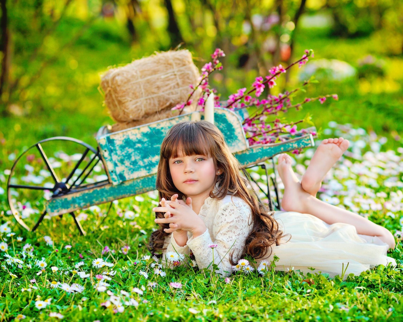 Маленькая девочка лежит на зеленой траве 