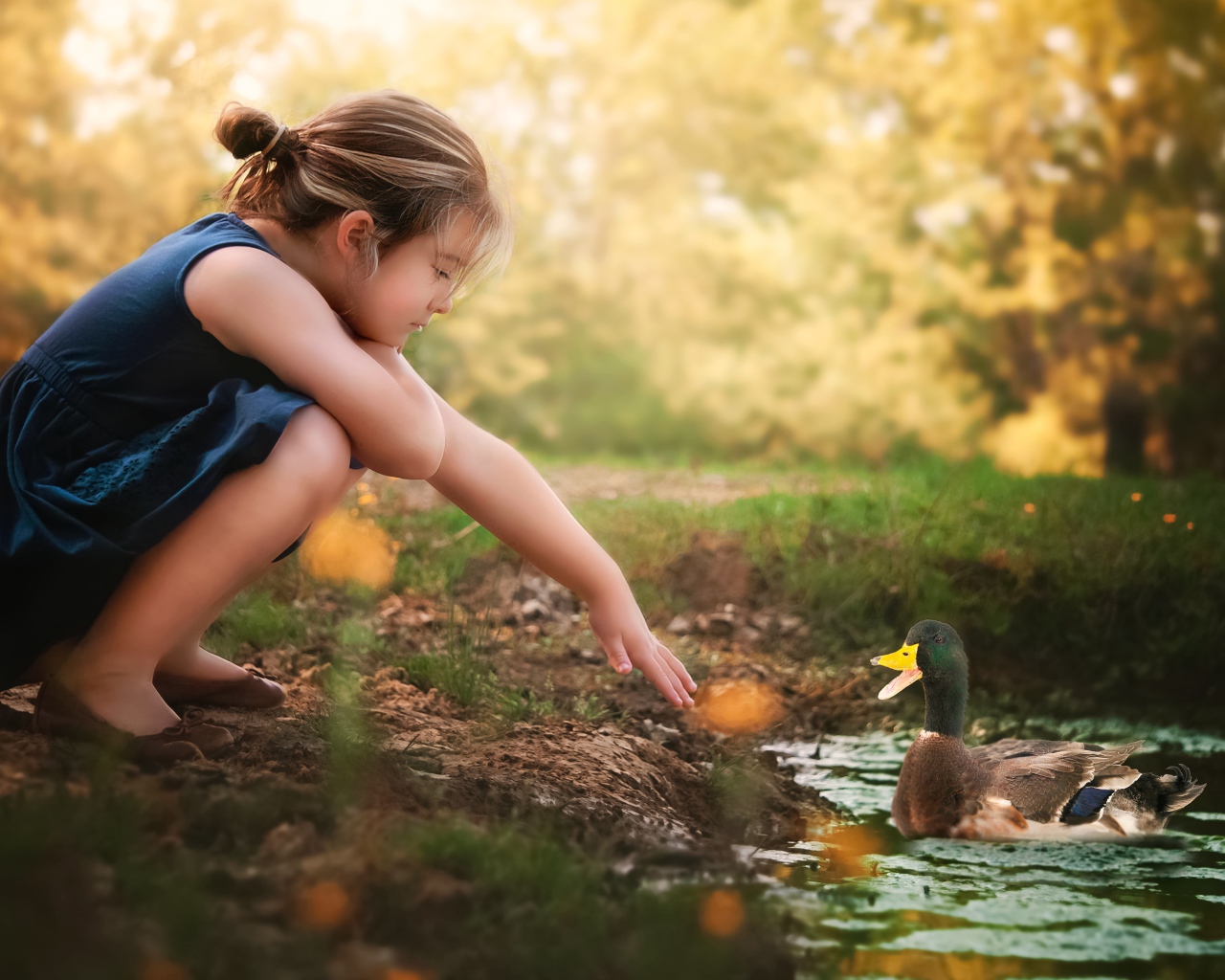 Маленькая девочка играет с уточкой в воде