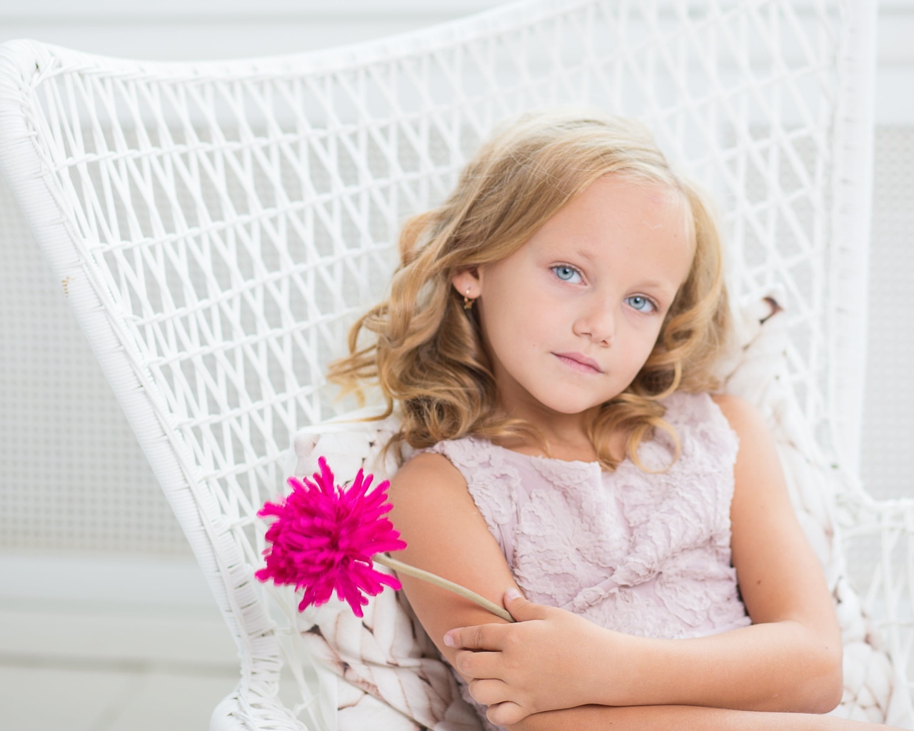Маленькая девочка сидит в белом кресле с розовым цветком