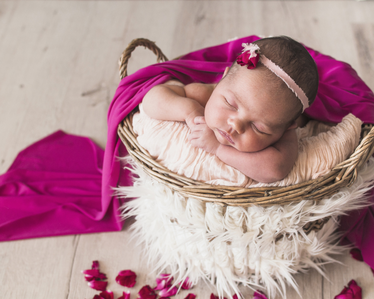 Маленькая девочка спит в корзине под покрывалом