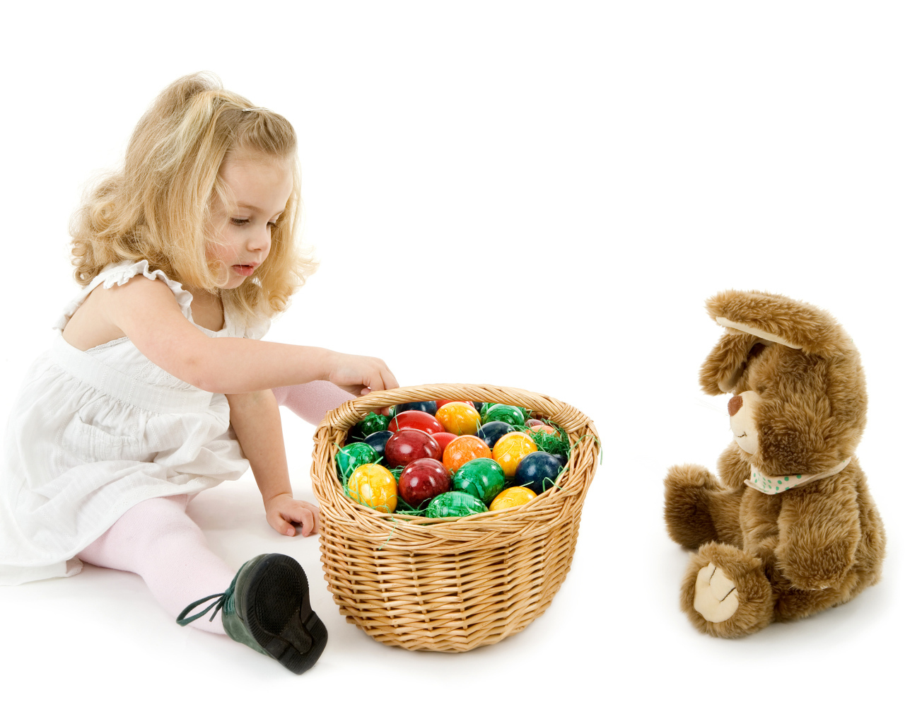 Маленькая девочка с корзиной крашеных яиц и игрушечным кроликом