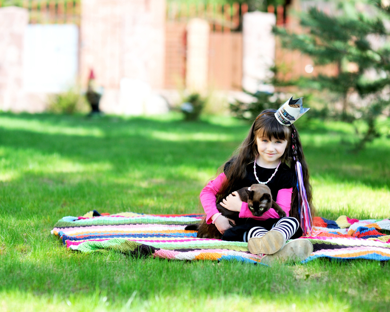 Маленькая девочка с котом сидит на зеленой траве