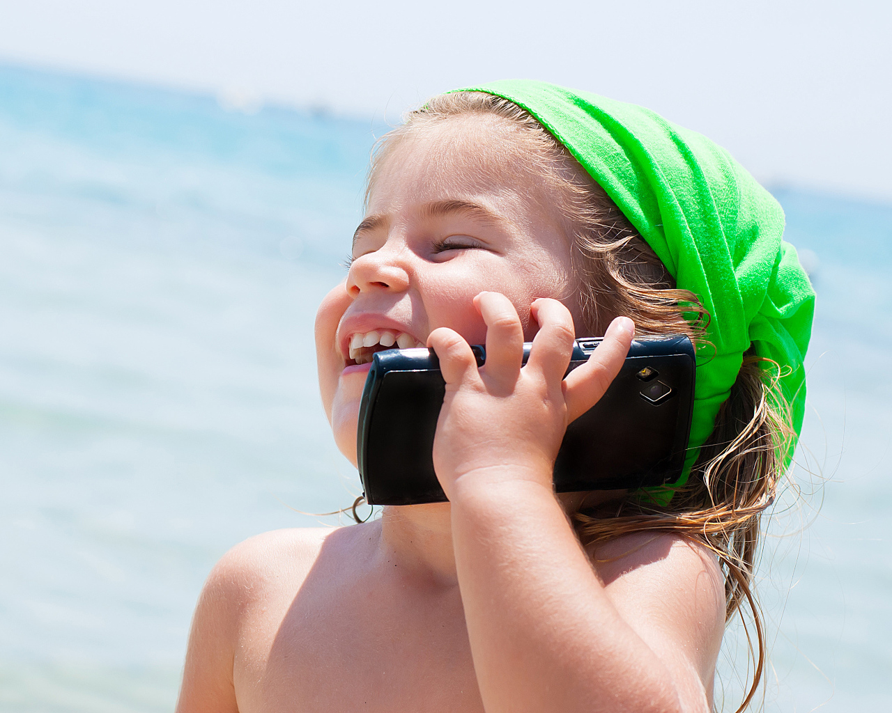Маленькая девочка с телефоном на пляже