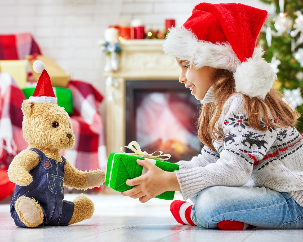 Маленькая девочка с медвежонком Тедди у елки с подарками на Новый год