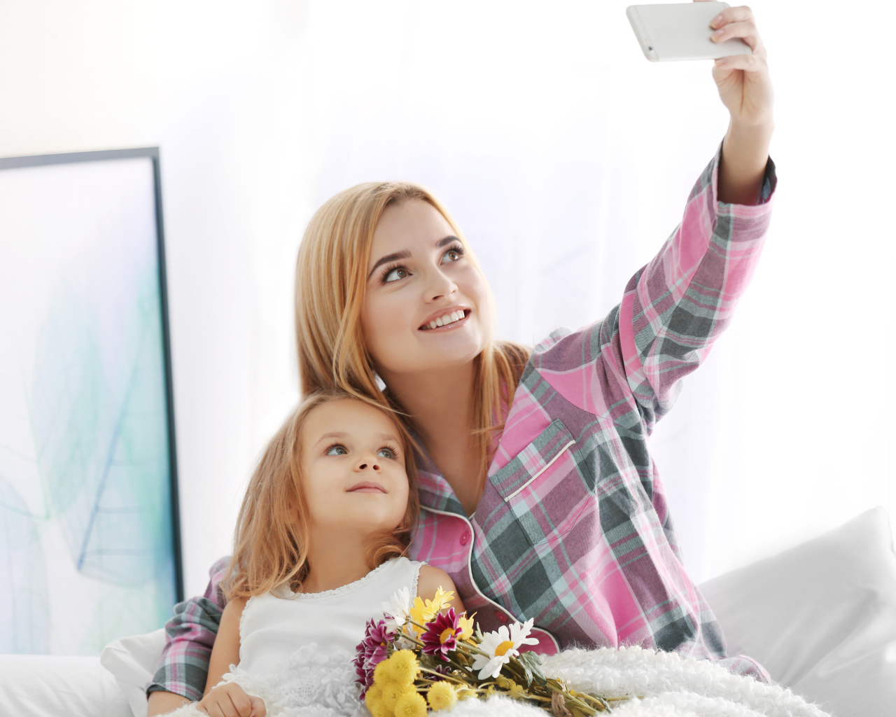 Маленькая девочка с мамой делают фото на смартфон