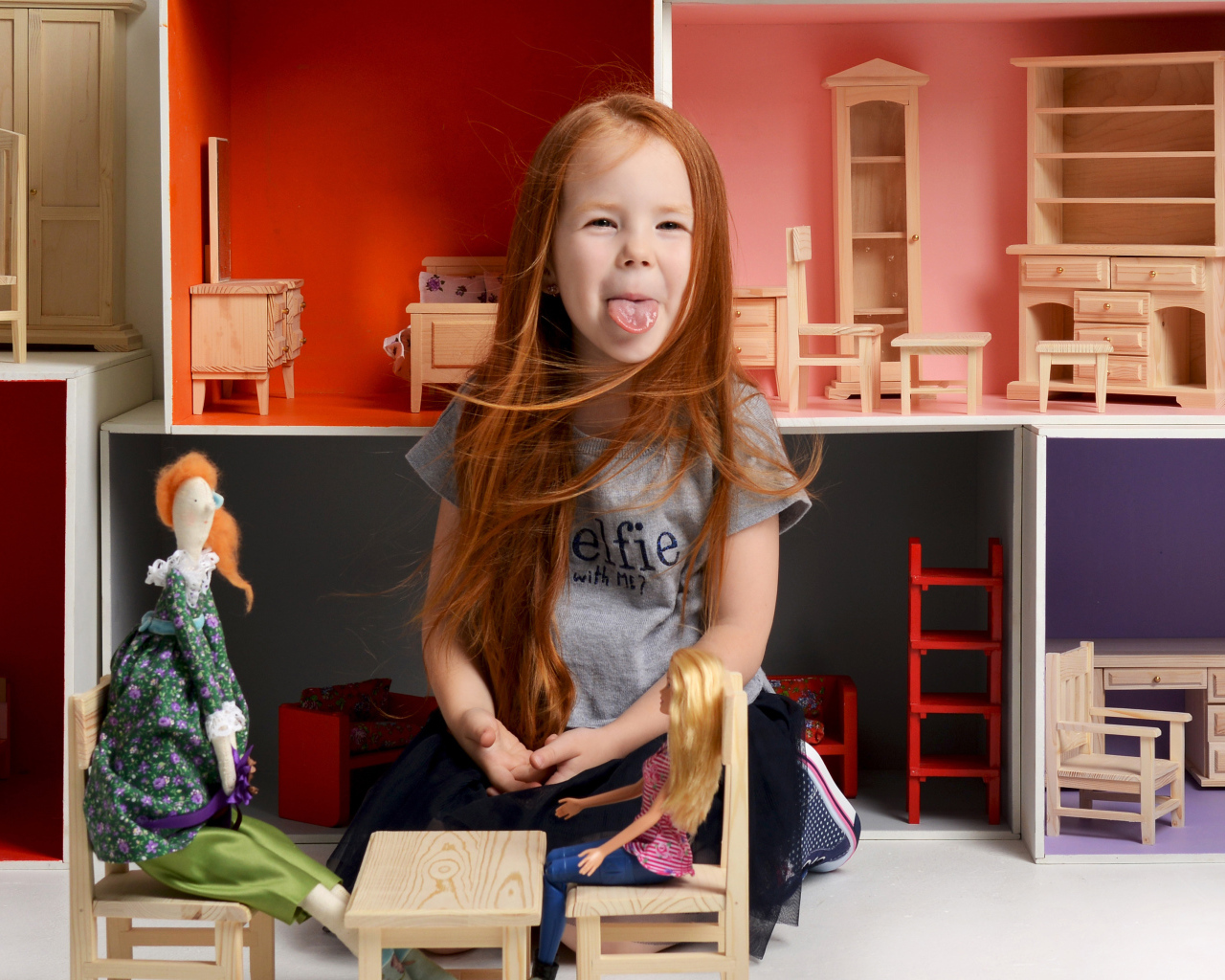 Маленькая длинноволосая девочка показывает язык