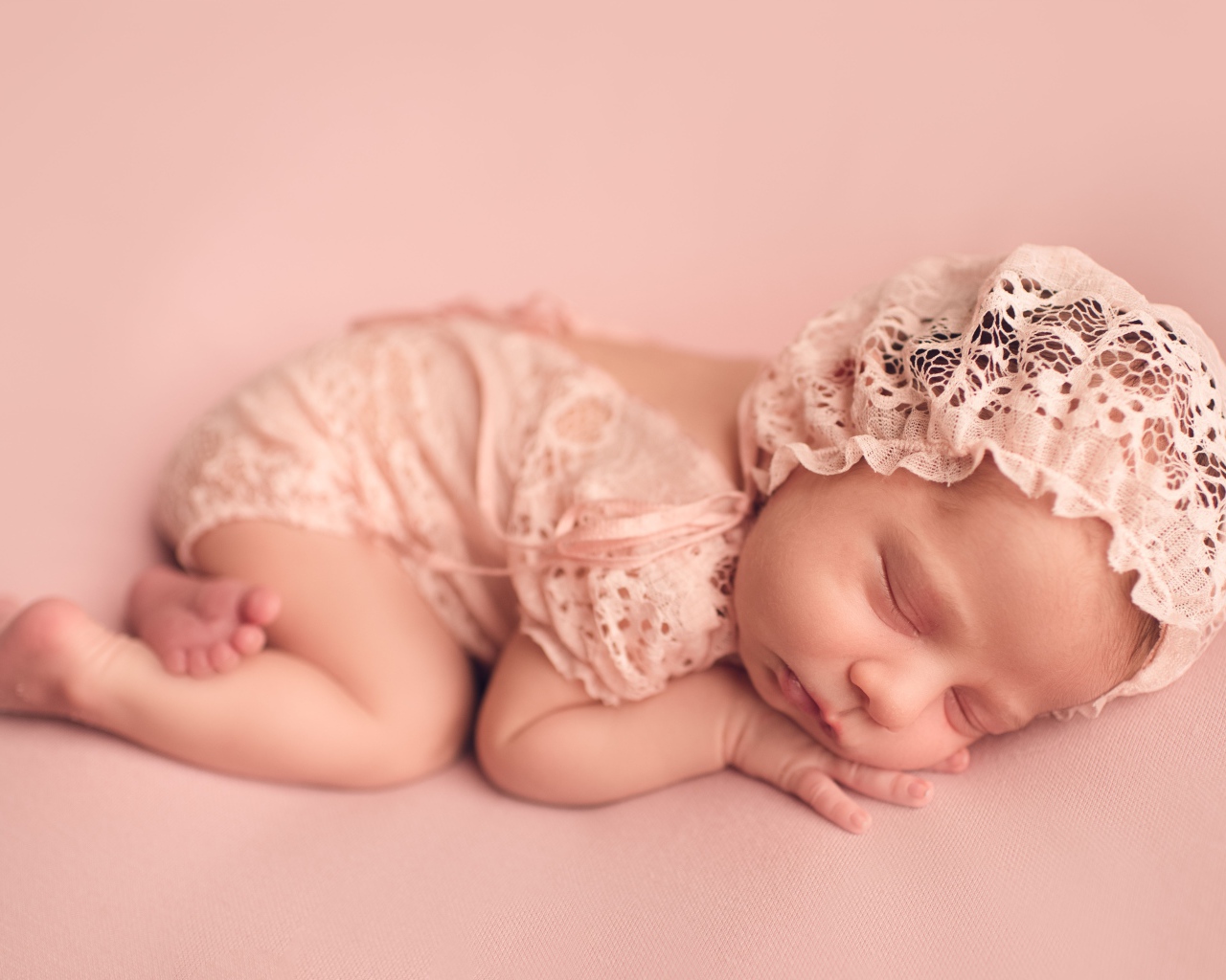Маленькая новорожденная девочка в розовом костюме 