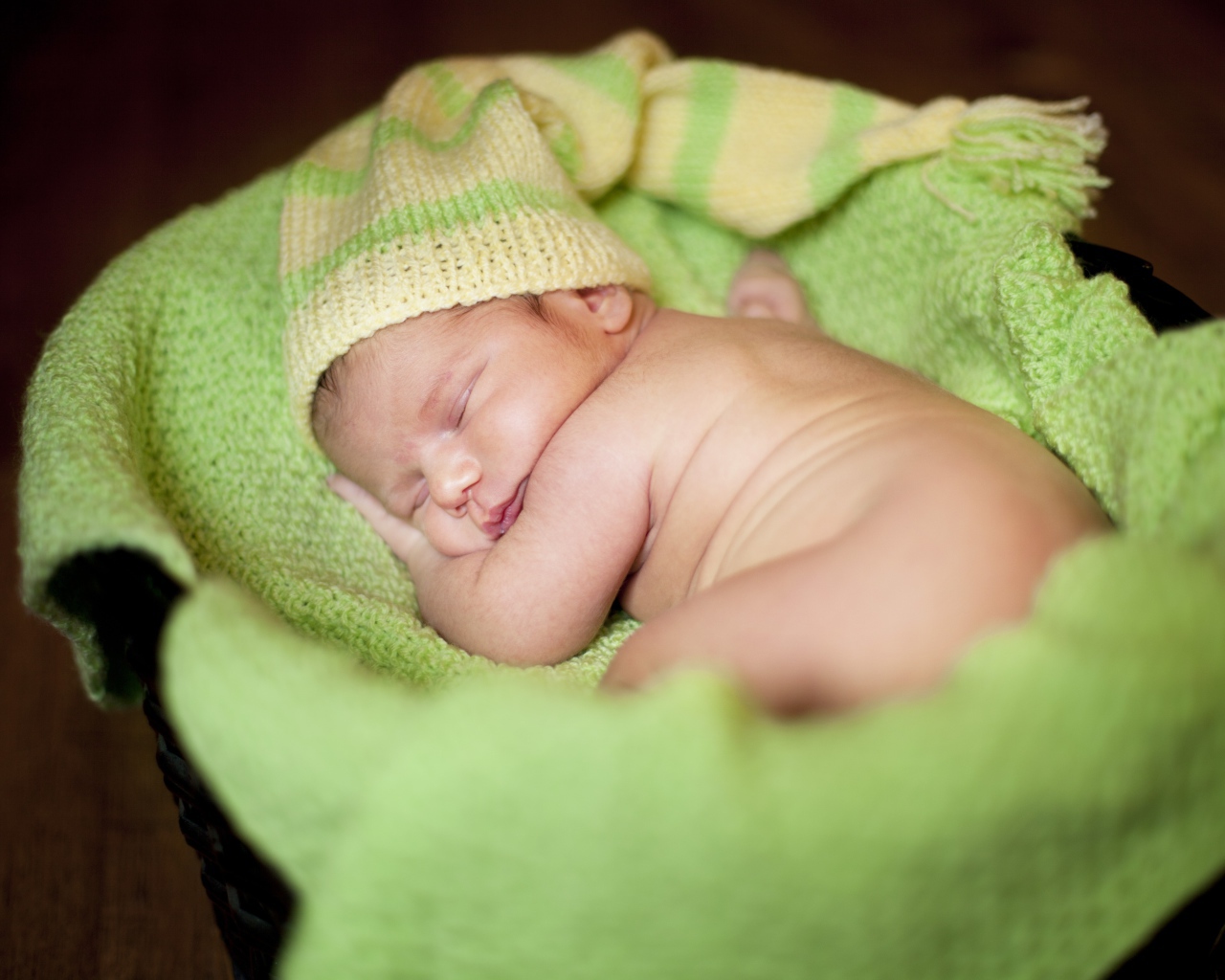 Маленький спящий грудной ребенок на зеленом покрывале 