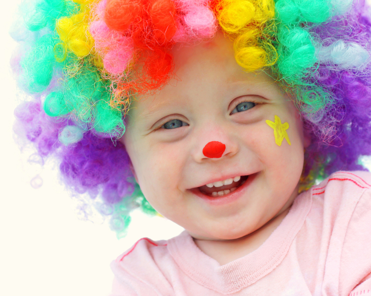 Маленький улыбающийся мальчик в костюме клоуна на белом фоне