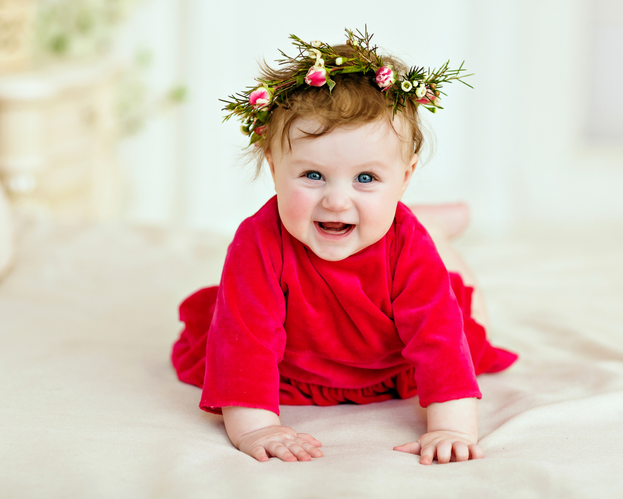 Маленькая улыбающаяся девочка в красном платье с венком на голове