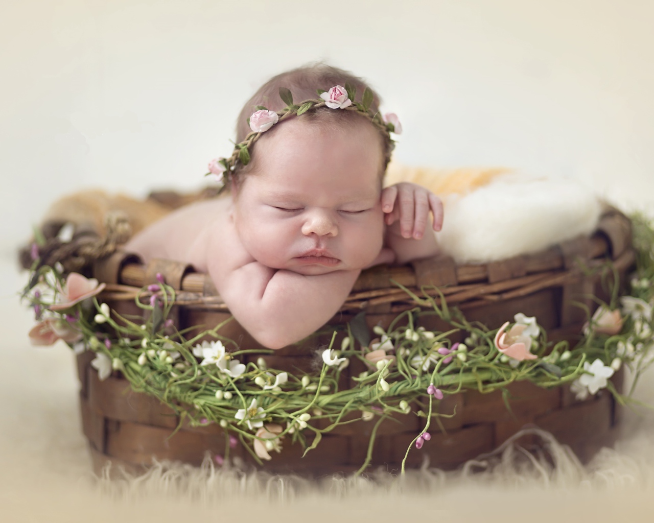 Спящий грудной ребенок в корзине с венком из цветов