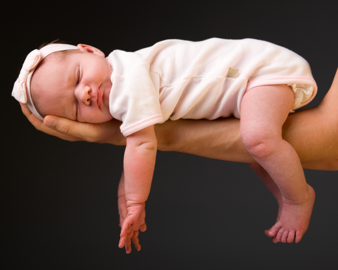 Спящий ребенок на руке у папы на сером фоне