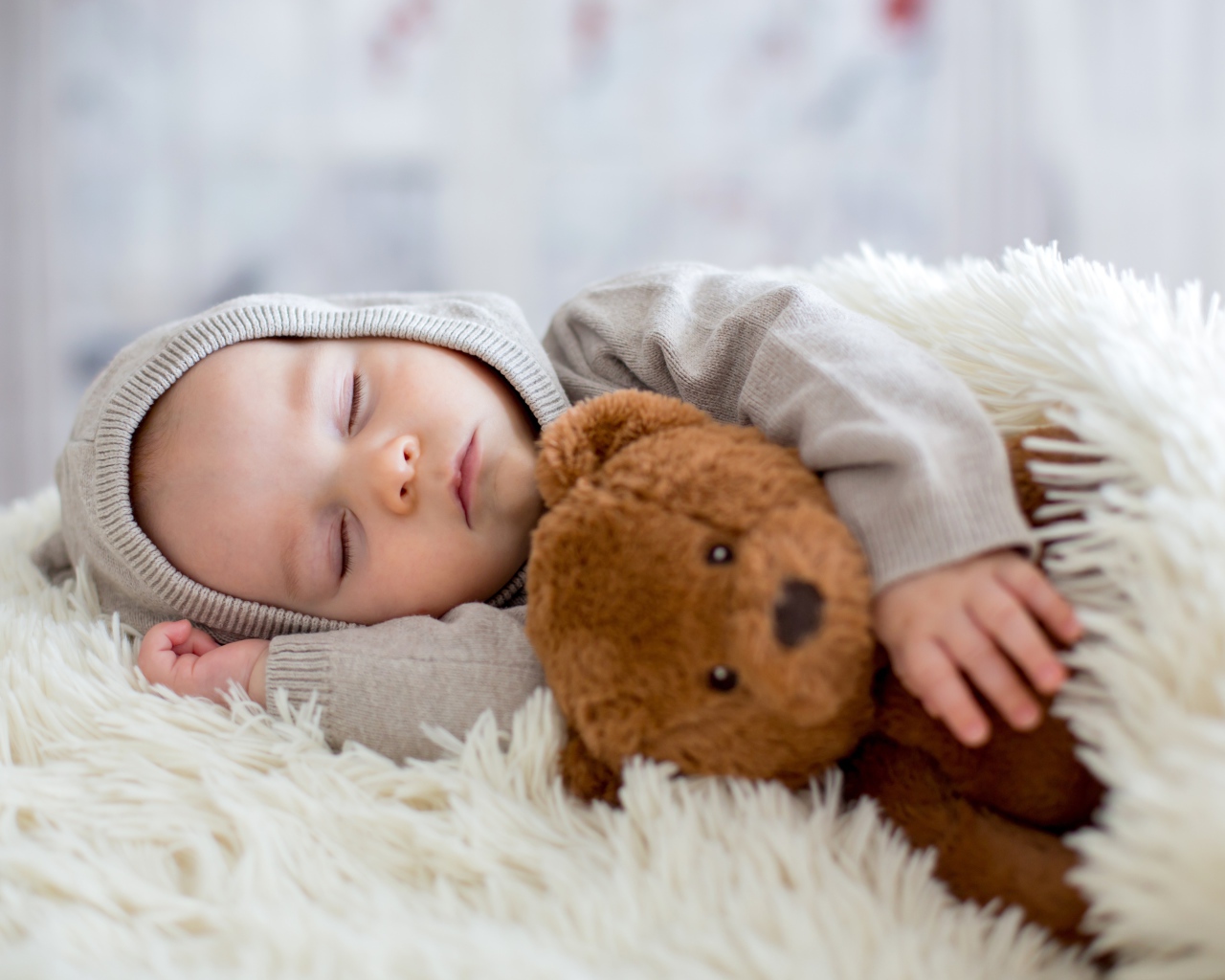 Спящий маленький мальчик обнимает игрушку медвежонка