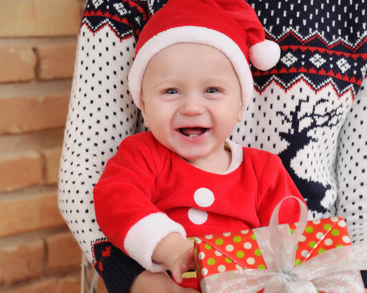 Улыбающийся малыш в костюме с подарком на руках 