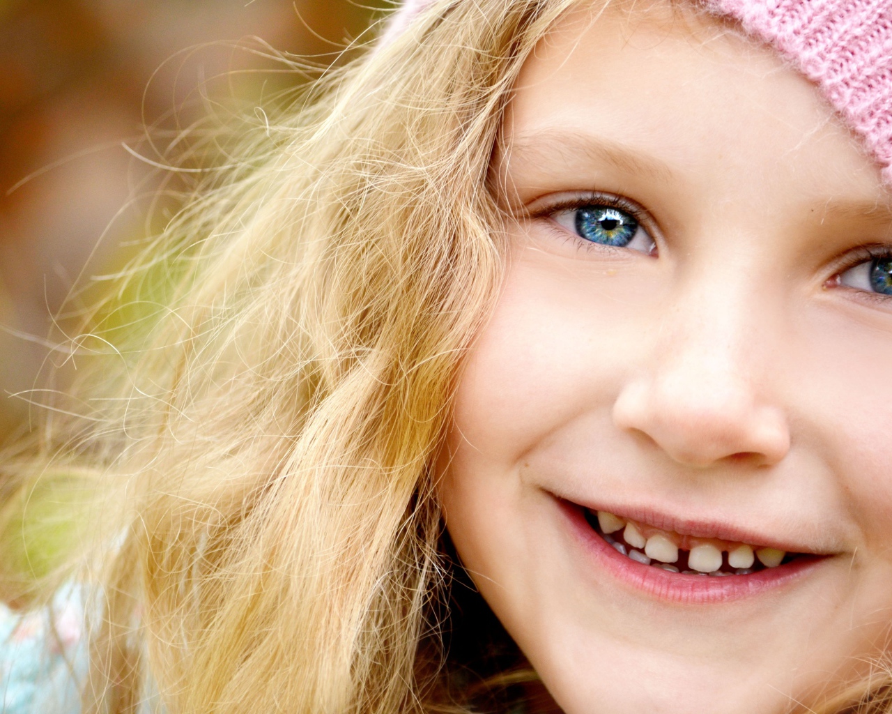 Улыбающаяся светловолосая девочка с голубыми глазами крупным планом