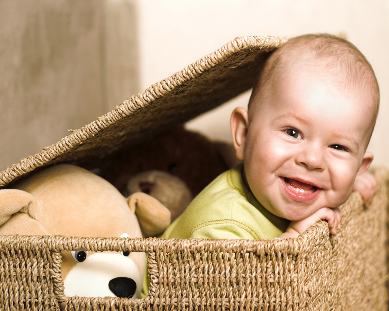 Улыбающийся забавный малыш в плетеной корзине с игрушками