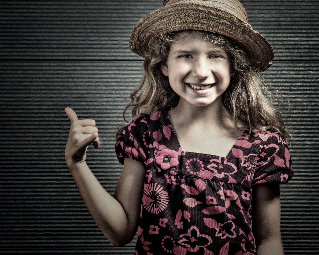 Улыбающаяся девочка в соломенной шляпе у стены 