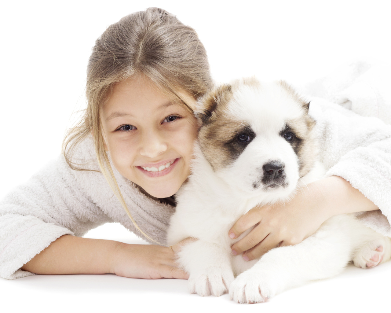 Улыбающаяся девочка лежит с щенком алабая