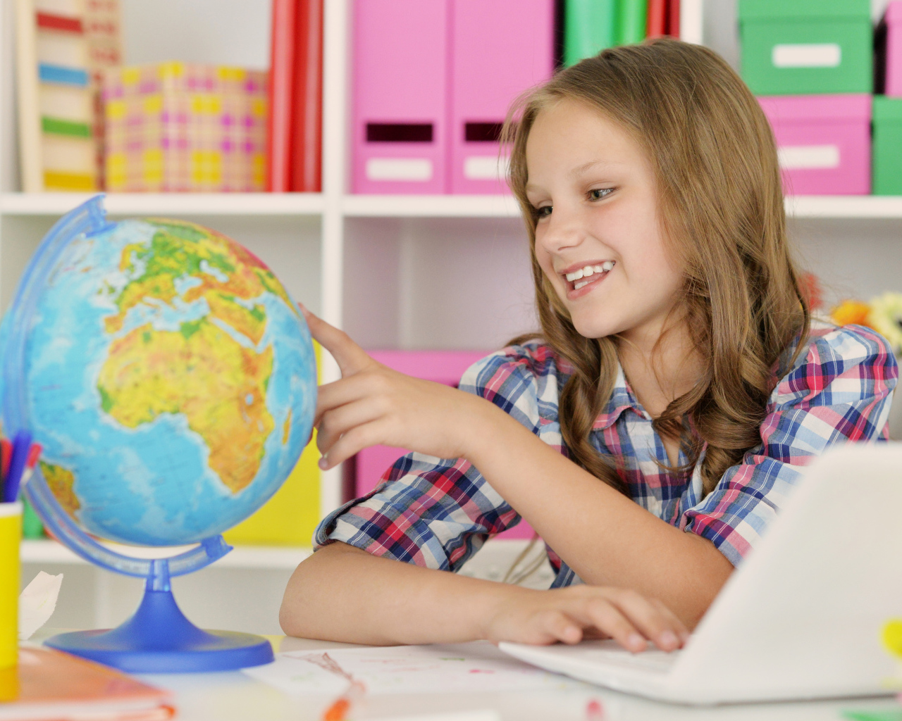 Улыбающаяся девочка школьница с глобусом