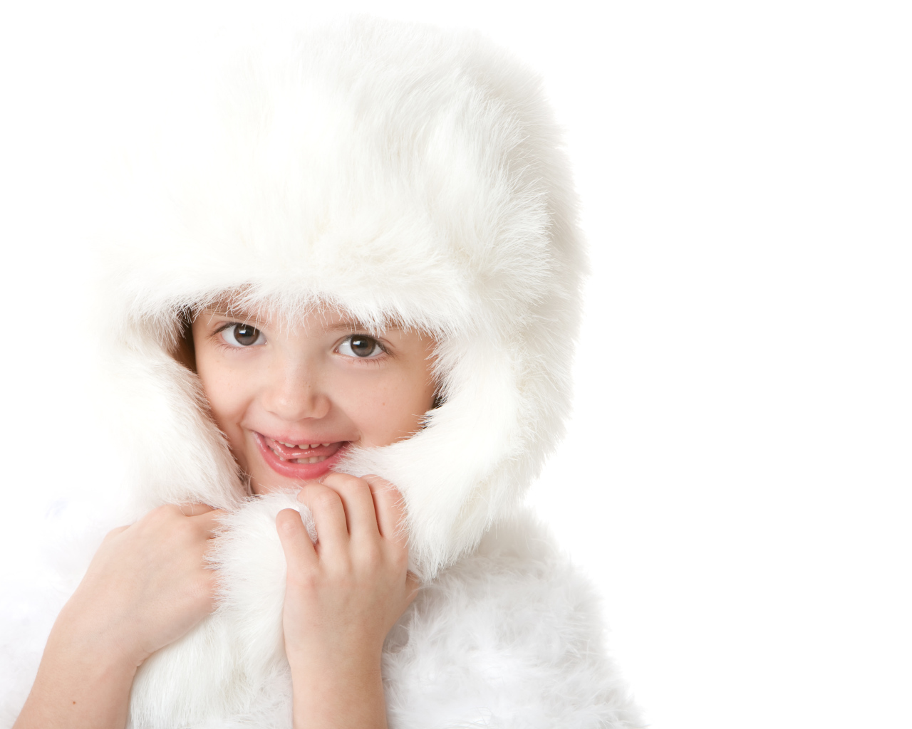 Улыбающаяся маленькая девочка в белой меховой шапке