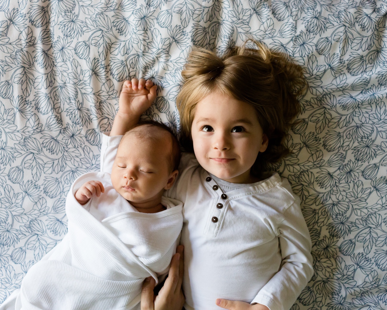 Маленькая девочка лежит с грудным ребенком