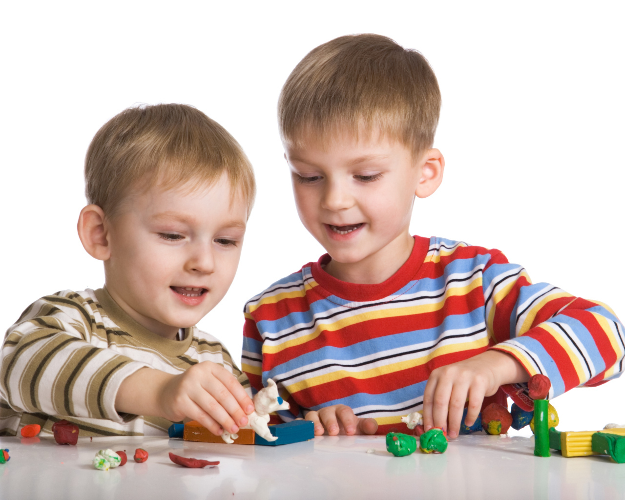 Два мальчика играют в игрушки на белом фоне