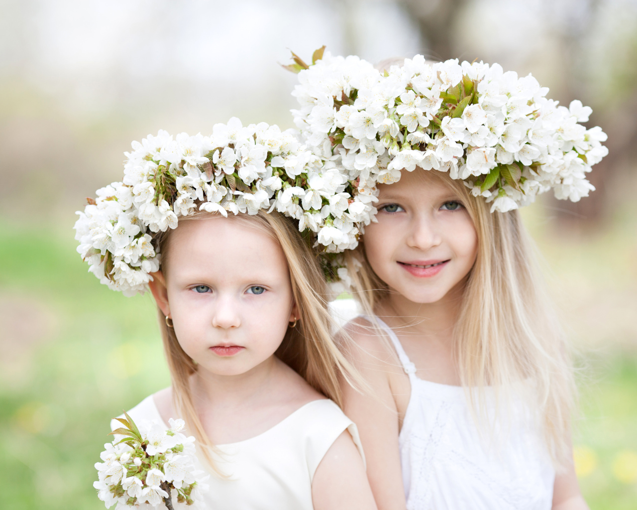 Две милые маленькие девочки с венками из цветов вишни на голове
