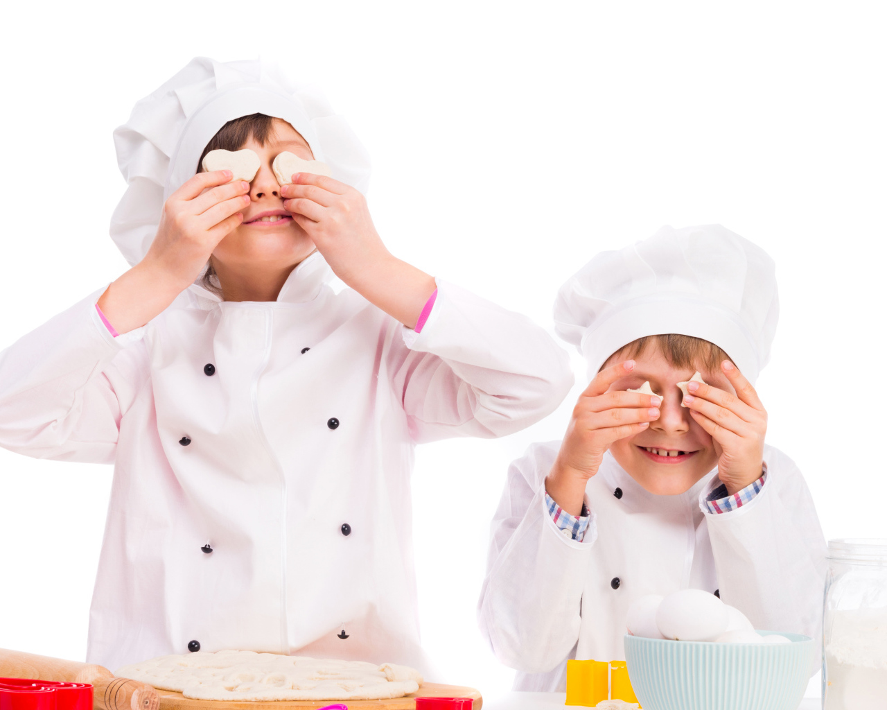 Два маленьких мальчика в костюмах повара на кухне делают печенье
