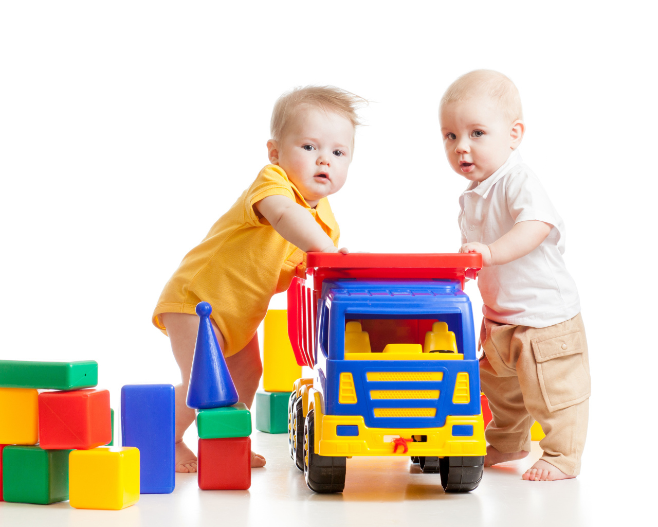 Два маленьких ребенка с игрушками на белом фоне