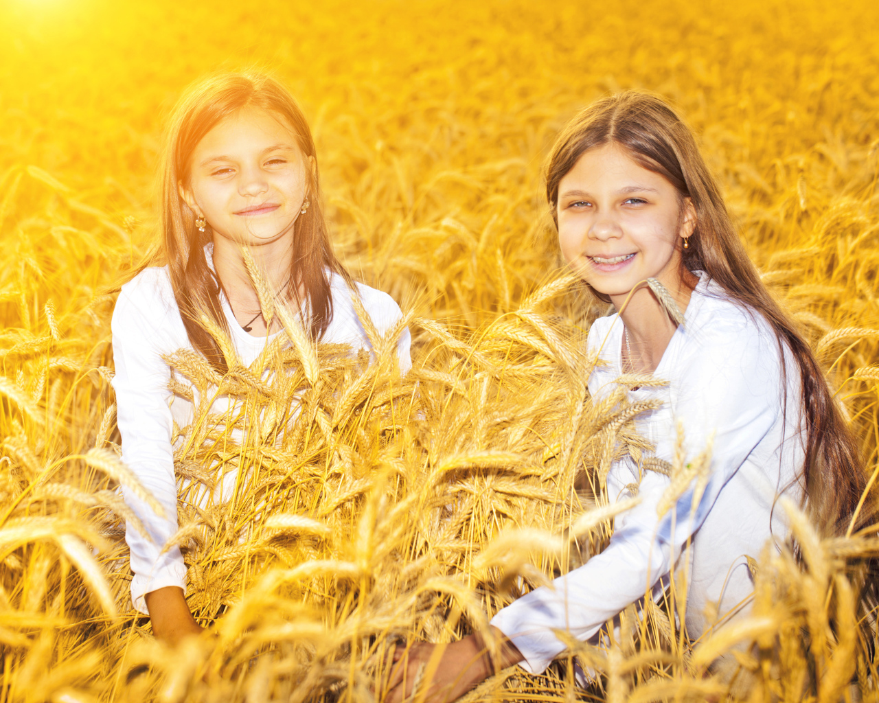 Две улыбающиеся девочки на поле с пшеницей
