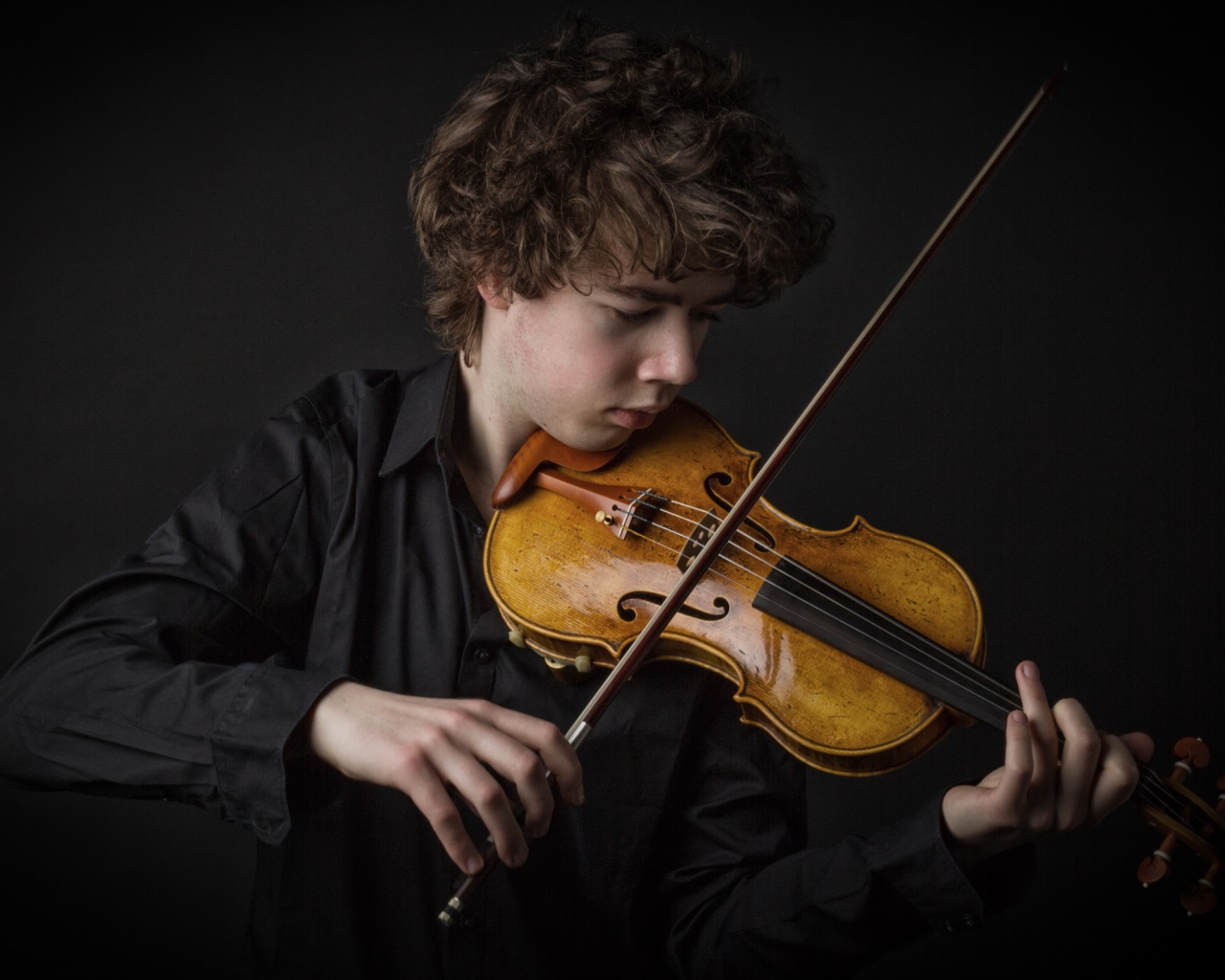 Молодой парень со скрипкой на черном фоне