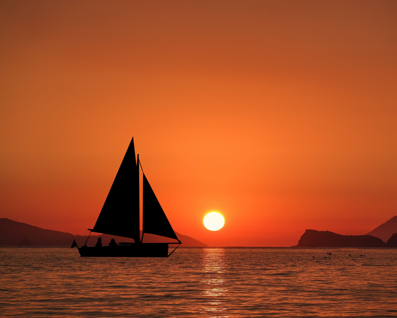 Парусная лодка в море на закате солнца
