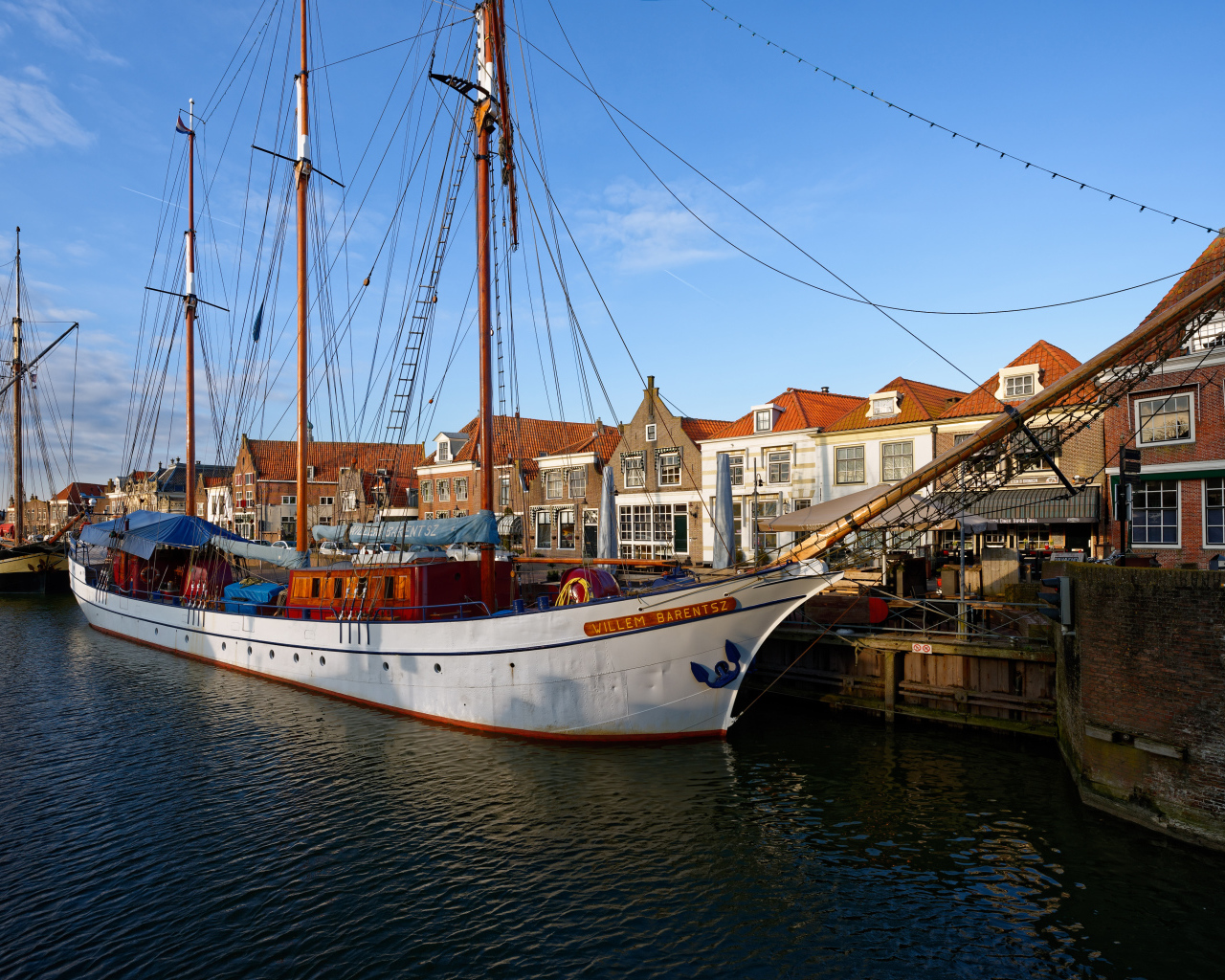 Парусное судно Willem Barentsz с опущенными парусами на причале у домов