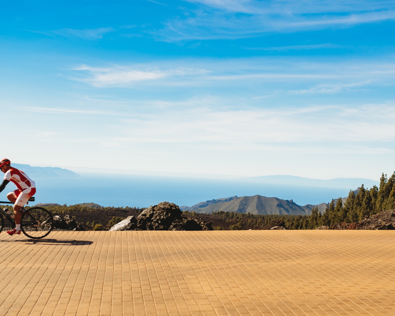 Велосипедист едет по дороге на фоне голубого неба
